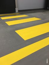 Фото четких контуров желтых линий напольной разметки для обозначения переходов движения персонала на путях движения складской техники